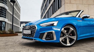 Sportliches Audi Cabrio im urbanen Umfeld Blaues Audi Cabriolet vor moderner Gebäudekulisse