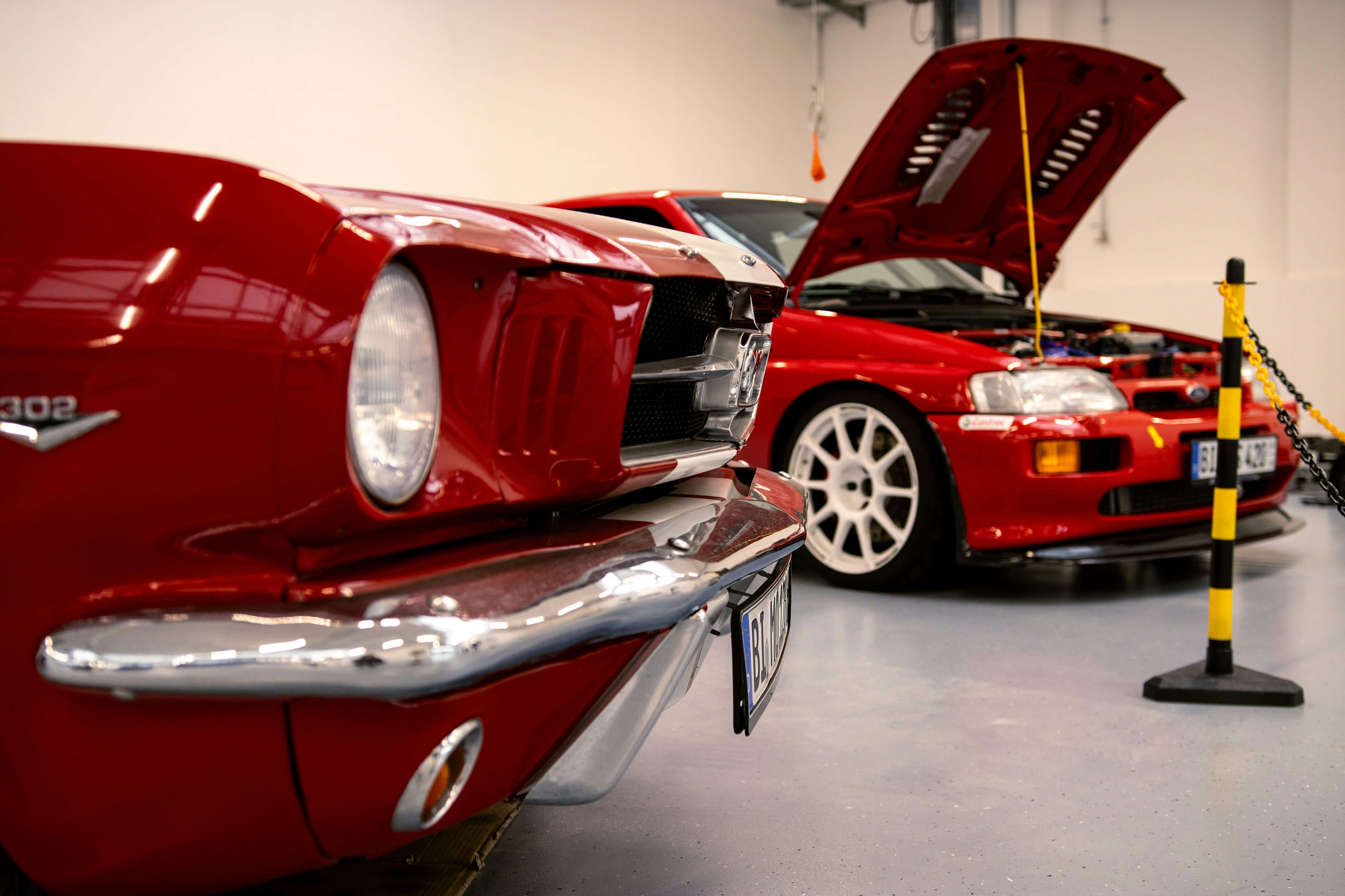 Ford Werkstatt für Klassiker – professionelle Pflege und Reparatur historischer Modelle. Ford Werkstatt mit zwei roten Oldtimern – einer davon mit geöffneter Motorhaube.