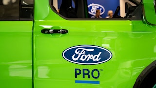 Ford Werkstatt mit Ford Pro – maßgeschneiderter Service für Gewerbekunden. Grüne Tür eines Ford Pro Fahrzeugs in der Werkstatt mit großem Markenlogo.