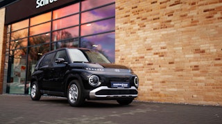 Schröder Teams Hyundai Angebote – attraktive Fahrzeuge zu Top-Konditionen Schwarzer Hyundai vor dem Schröder Teams Autohaus mit reflektierendem Schaufenster und aktuellen Angeboten