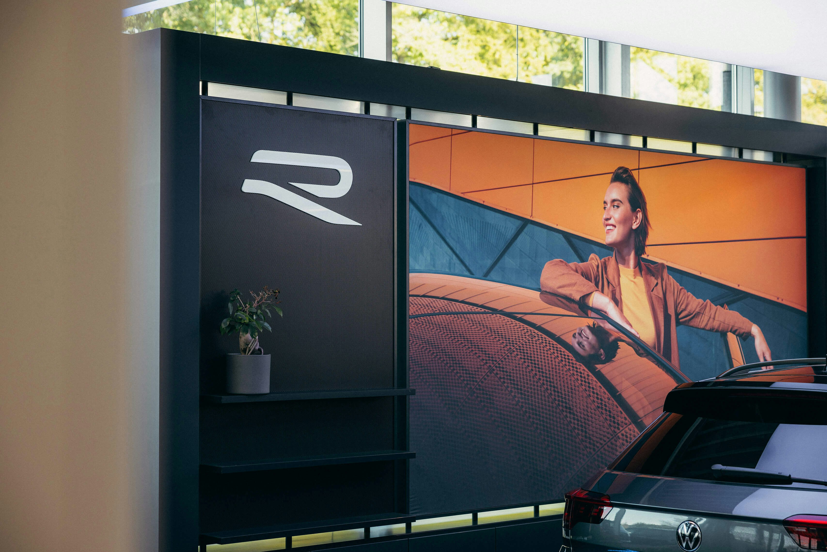 VW Angebote mit sportlichen R-Line Modellen im Autohaus VW R-Line Präsentationsfläche mit Plakat und Fahrzeug – emotionale VW Angebote erlebbar gemacht