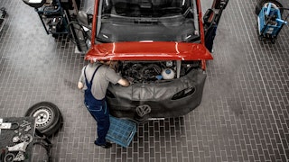 Arbeiten in unserer VW Nutzfahrzeuge Werkstatt Mechaniker arbeitet am Motorraum eines roten VW Nutzfahrzeugs in unserer VW Nutzfahrzeuge Werkstatt