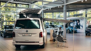 VW Nutzfahrzeug-Angebote im Autohaus – VW California im Ausstellungsraum VW California mit Markise und Campingausstattung im Showroom des Schröder Teams – jetzt VW NFZ Angebote entdecken
