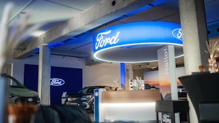 Empfangsbereich mit Ford-Branding in moderner Verkaufshalle Ford-Empfangsbereich mit Logo-Elementen, modernem Tresen und ausgestellten Fahrzeugen in heller Halle